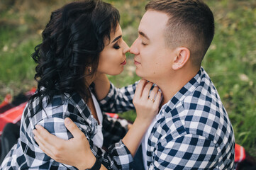 A beautiful girl with curly hair and a guy in plaid shirts hug and rub their noses gently. Close-up portrait of faces.