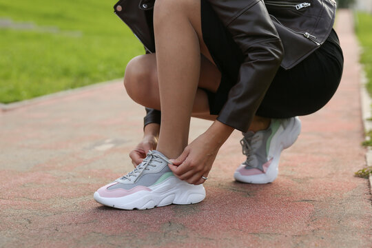 Woman Tying Laces On Sneakers On The Street