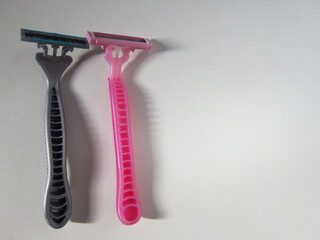 Men's and women's razors on gray background, hygiene concept.