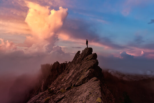 Adventurous Girl on top of a rugged rocky mountain. Dramatic Colorful Sunrise Sky Art Render. Taken on Crown Mountain, North Vancouver, BC, Canada.