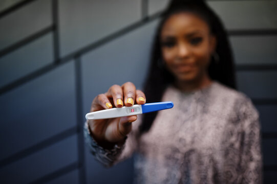African american woman feeling surprise hold pregnancy test.