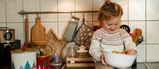 Christmas. Adorable 3 year old girl eating Christmas cookies and drinking hot tea in New Year's decorations. Winter holidays.