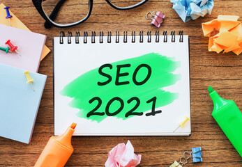 Office wooden table with a notebook SEO 2021 with markers, paper clips, crumpled paper. Business...
