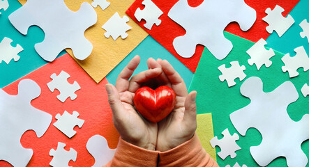 Creative design for Autism World Awareness day on April 2. Flat lay, hands holding red stone heart.