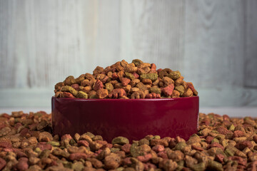 studio lighting. animal feed is scattered on it, there is a bowl in it, a granule is poured.