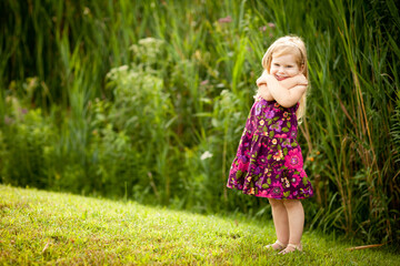 Fototapeta premium Little Girl with Blond Hair Enjoying a Summer Day Outside, Childhood Lifestyle Portrait