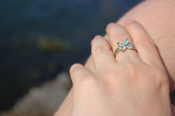 Female fingers with a beautiful ring with a flower-shaped ending with shimmering crystals.