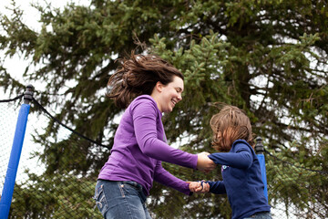 Happy Mother and Daughter Jumping on Trampoline Together