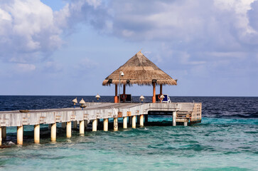 View of the pier, azure ocean water and cloudy sky in the tropics.