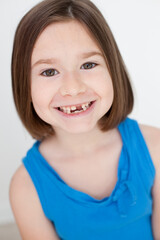 Fototapeta premium Smiling Little Girl with Brown Hair and Missing Teeth, Happy Childhood Portrait