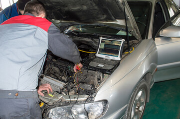 Electrician and mechanic check the car with the help of oscilloscope