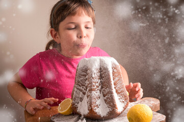 Little girl blowing icing sugar off the Soft star-shaped pasta. Traditional Italian pastries from...