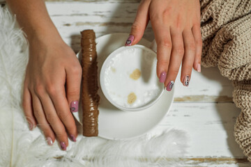 Woman's hands in sweater holding cup of coffee on wooden table.chocolate on a plate