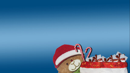 Bear in a red cap of Santa Claus with gifts on a black background.
