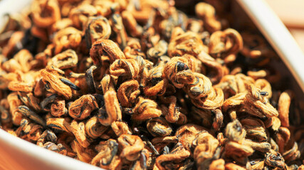 Chinese red tea Golden Curls (Dianhong Jin Luo) high quality with red furry tea buds. Macro image with blurred background.