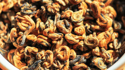 Chinese red tea Golden Curls (Dianhong Jin Luo) high quality with red furry tea buds. Macro image with blurred background.