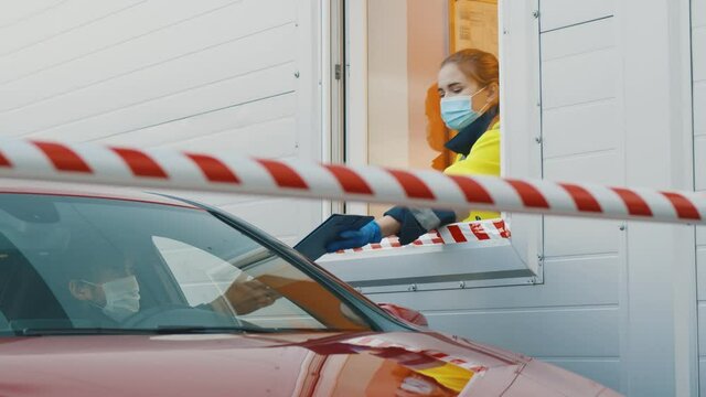 Man in car wearing safety mask signing document at checkpoint of private area