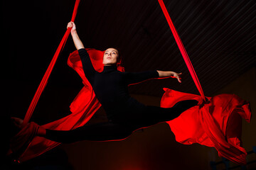 Girl aerialist doing twine on aerial canvases. Acrobatics in the air