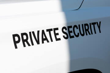 Private Security text sign on the side of white patrol vehicle used by a private security service company. Close up.