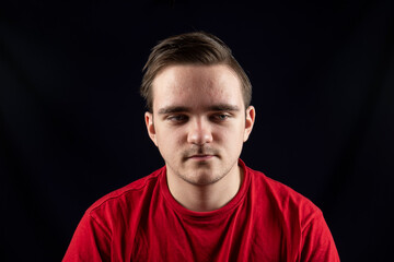 Young man in casual t-shirt standing against isolated dark background