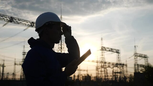 Electrical Silhouette Worker Engineer A Working With Digital Tablet, Near Tower With Electricity. Energy Business Technology Industry Concept. Electrical Studying Reading Documents On Tablet Power