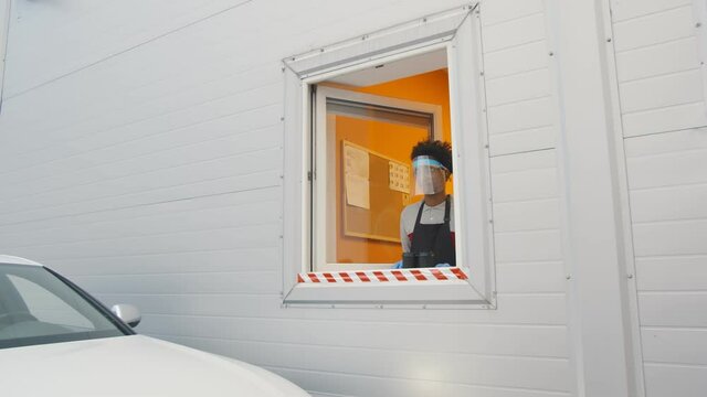 Man driver getting takeaway coffee at drive thru restaurant