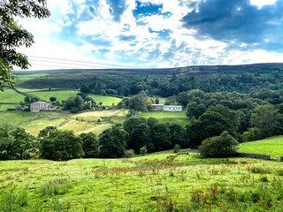 Obraz premium Landscape view from, Hey's Lane, with sloping fields, farms, meadows, and trees in the distance in, Wainstalls, Halifax, UK
