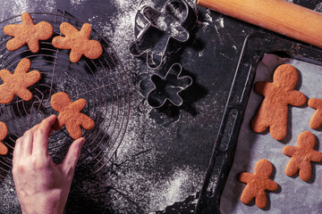 Man putting fresh baked gingerbread cookies on cooling tray, top view. Christmas preparations.