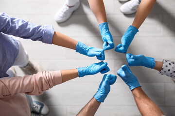 Fototapeta na wymiar Group of people in blue medical gloves showing thumbs up indoors, top view