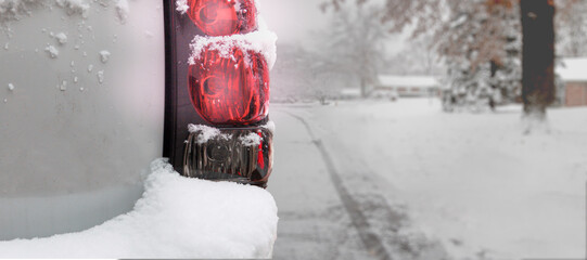 Closeup of a white SUV car taillight driving along a road covered in snow - winter white palette
