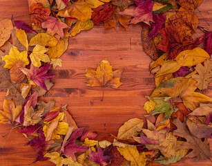 red, orange, green, brown, yellow dry leaves frame. wood table. autumn background. top view with copy space.