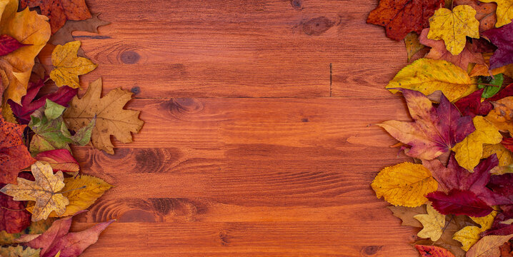 red, orange, green, brown, yellow dry leaves frame. wood table. autumn background. top view with copy space.