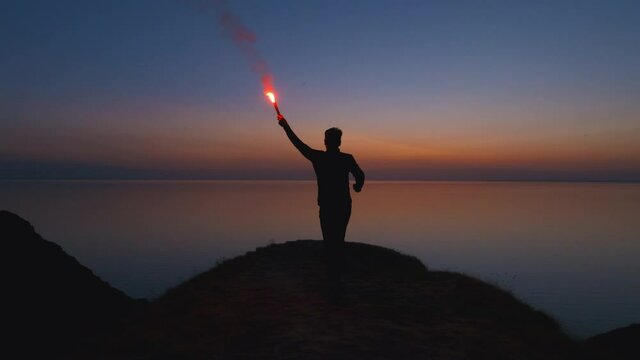 The man runs with a burning fire stick on the seascape background. slow motion