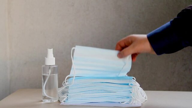 Close-up of woman and mam hand using sanitizer and mask to protect agaist coronavirus. Covid-19 protective measures.