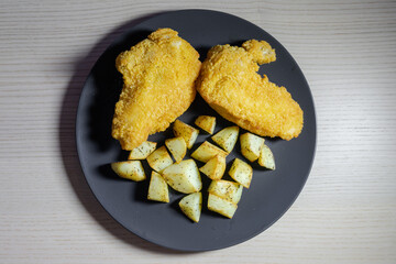 Two pieces of crumbed chicken with baked potato.