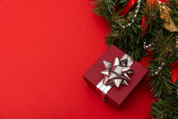 red little gift on a red background with a silver bow with Christmas decorations