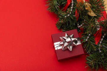 red little gift on a red background with a silver bow with Christmas decorations