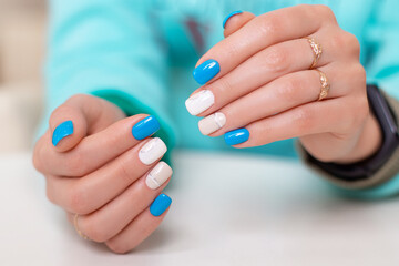 Beautiful female hands with romantic manicure nails, blue and white gel polish