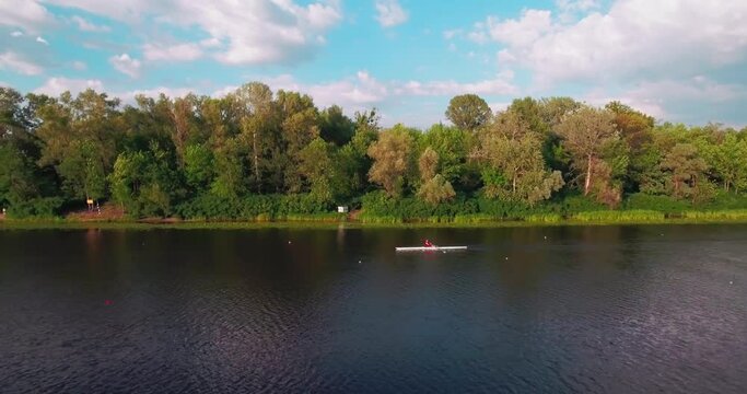 Drone shot at an athlete training in a sports kayak katoraya floats on the river at sunset.