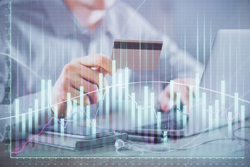 Double exposure of man hands holding a credit card and Forex graph drawing. Stock trading and digital fintech in Internet E-commerce concept.