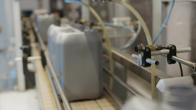 Plastic gallons or bottles on production line at filling machine in factory.
