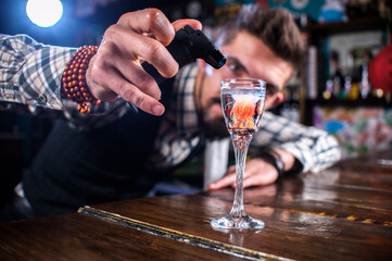 Bearded barman is pouring a drink while standing near the bar counter in nightclub