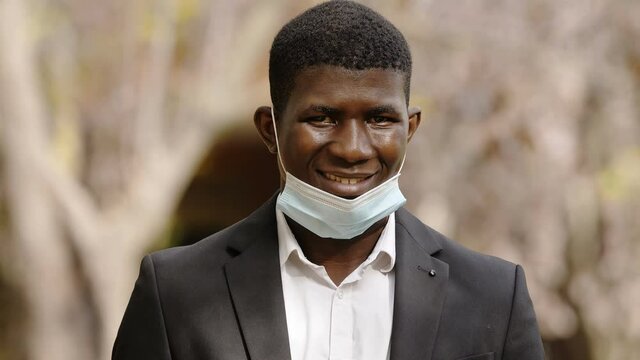 positivity, hope - young black man with the mask pulled down smiles at camera