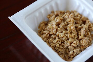 A close up shot of some finely chopped fermented soybeans in a small styrofoam packet. 