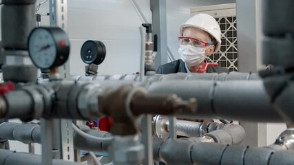 Maintenance engineer in safety mask checking technical data of heating system equipment at factory