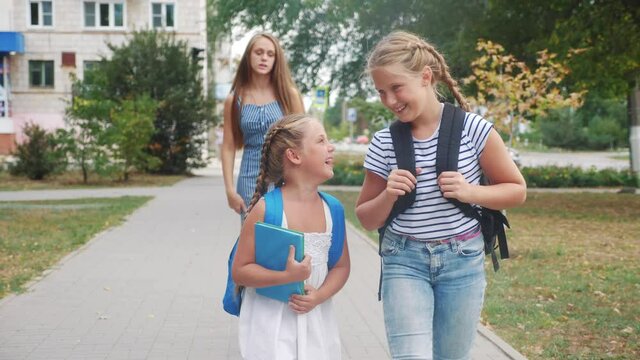 group of schoolchildren walking to school along the path. happy family school concept.little schoolgirl with backpack and textbook. schoolgirls walk education along in the park school to for lessons