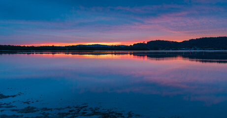 Reflection of Sunrise with soft high cloud over the waterfront