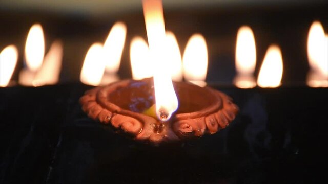 Clay Diya or Oil Lamps lit during the Diwali night. Traditional Diyas lit on gold and black background