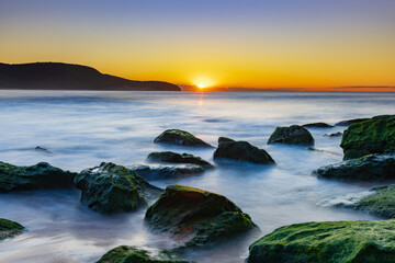 Sunrise by the Sea and Rocks on the Shoreline