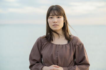 夕方、海をバックに撮影された若い女性のポートレート